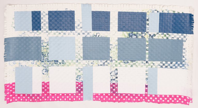 an abstract mixed media piece made up of woven paper dyed with a bright fuchsia at the bottom with white color blocks in a row above that, then a mid-toned blue row of color blocks in the middle, then a darker blue row of color blocks on top. in the background of these colorblocks is a blue and green silkscreen painting very subtly creating dimension in the piece.