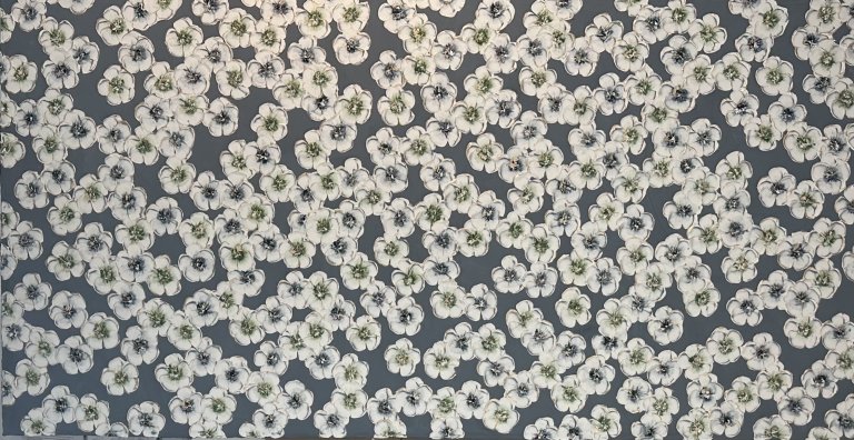 an abstract floral piece with a dark slate blue background. the foreground is a smattering of white blossoms. each flower has a dark green or an indigo center.