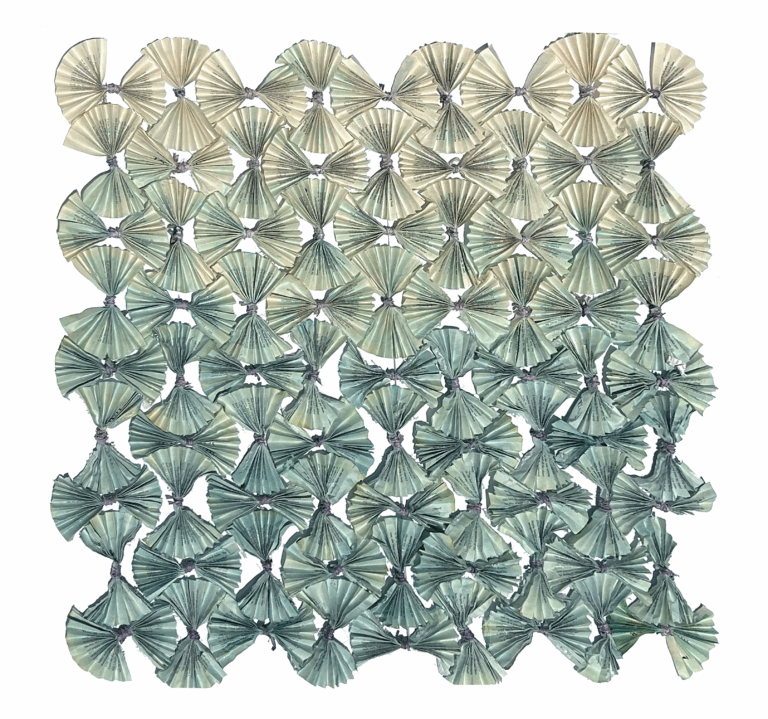 a folded piece of artwork where paper is folded accordion style and arranged in a square shape. the color changes from top to bottom in a gradient. the top is a soft tan and fades to a light green/aqua at the bottom