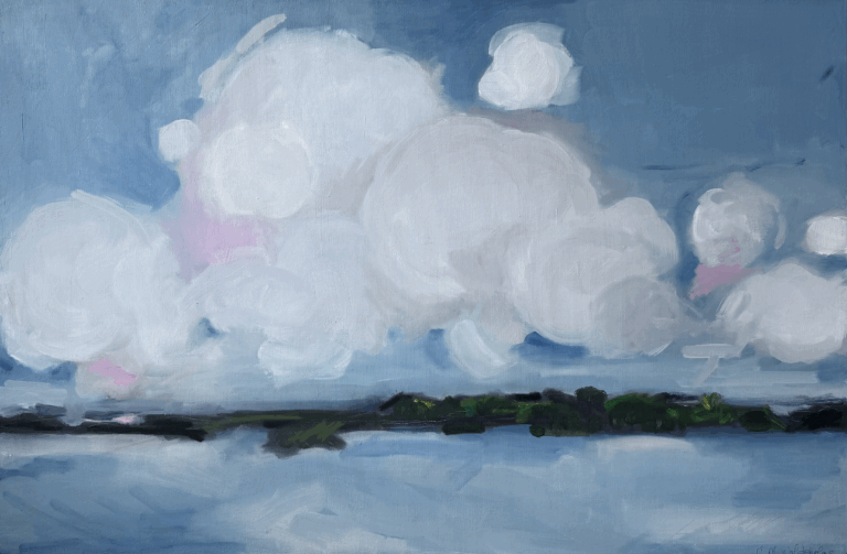 a fluffy cloudscape with pink accents against a blue sky above a body of water lined with green foliage.