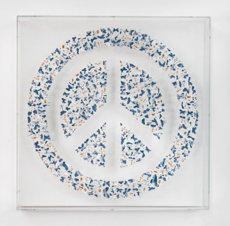 a 3d piece of artwork that depicts a peace sign made of tiny butterflies cut from blue, white, and gold disposable coffee cups