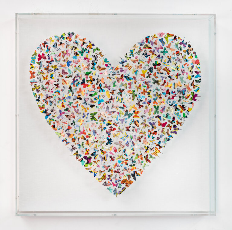an abstract art piece made of small butterflies cut from comic book pages and mounted on pins, then arranged in the shape of a heart