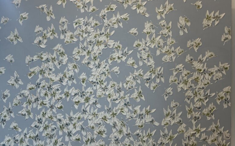 an abstract piece of butterflies with pointed white wings with indigo and chartreuse centers against a light blue background