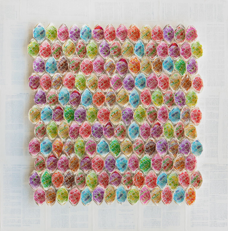 a collage of multi colored lollipop wrapper made into canoe shapes and arranged svertically ide by side