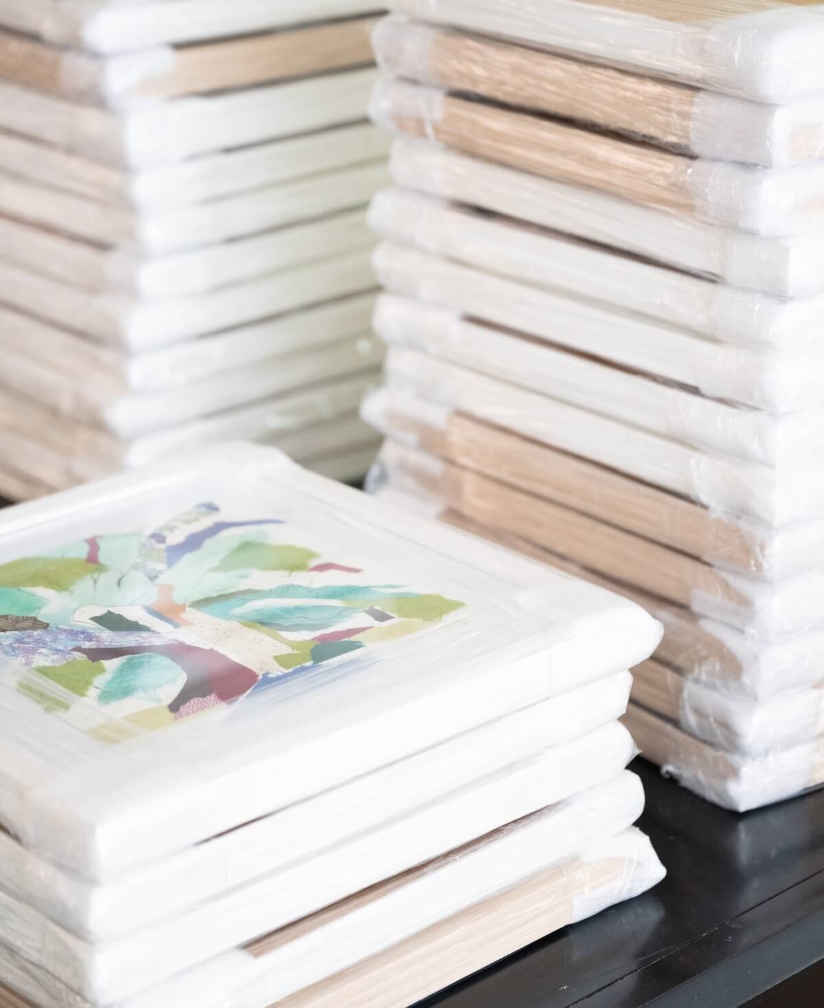 many framed pieces of art stacked on top of one another